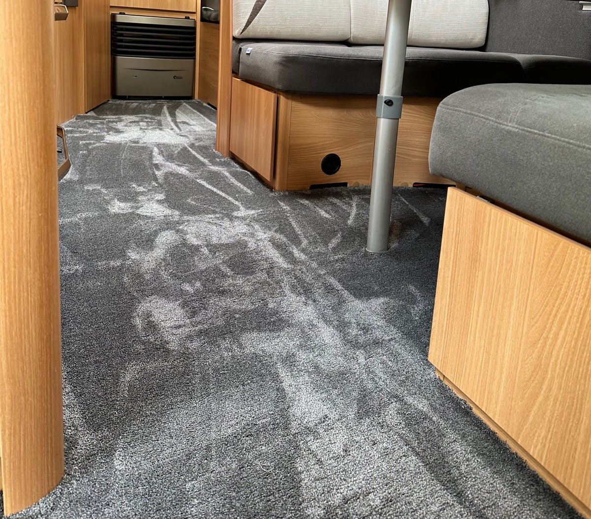 Neu verlegter grauer Teppich im Wohnwagen zwischen Sitzbank und Möbeln